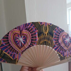 Éventail bohème tenu à la main, motif cœurs et mandalas